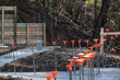 Construction site on hillside with footings poured and rebar with orange safety caps, horizontal aspect
