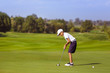 © alexsokolov - Boy golf player putting at green at sunny day