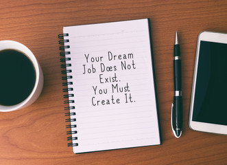 Wall Mural - Life Inspirational And Motivational Quotes - Your Dream Job Does Not Exist. You Must Create It. Notepad With Coffee, Pen and Smart Phone.