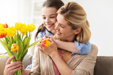 happy girl giving flowers to mother at home