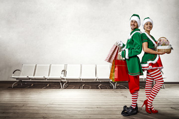 Two Christmas elves in the waiting room. a large wooden floor, white chairs and a white wall with space for your inscription. Christmas advertising background.