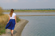 © smoskvitin - a woman in a blue skirt walking along the river