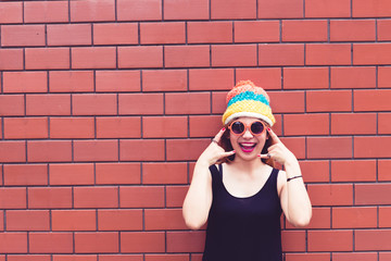 Wall Mural - Asian hipsters girl  on orange brick wall,lifestyle of modern teenage,Happy lady posing for take a photo,thailand people,orange sunglass,vintage,film tone