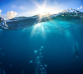 Wall Mural - underwater scenery, deep blue water of the ocean, air bubbles, waterline splitting skyline, divers d