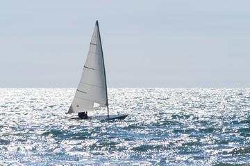 sailboat sails on a sparkling sea in a windy day