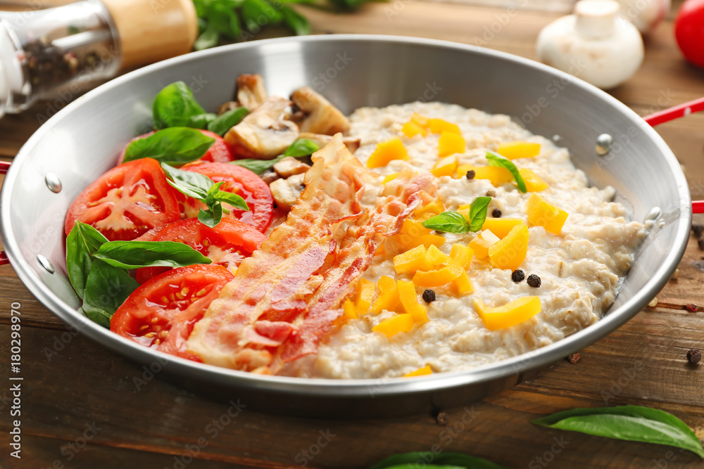 Dish with oatmeal porridge, bacon and garnish on table