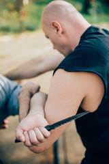 Wall Mural - Kapap instructor demonstrates martial arts self defense knife attack disarming