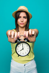Sad woman holding alarm watch showing 8 clock isolated portrait on green background