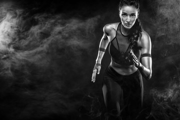 Wall Mural - A strong athletic, woman sprinter, running on black background wearing in the sportswear, fitness and sport motivation. Runner concept with copy space.