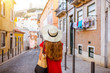 Woman tourist walking back on the narrow street in Alfama region during the morning light in Lisbon, Portugal