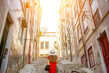 Wall Mural - Woman tourist walking back on the narrow street in Alfama region during the morning light in Lisbon, Portugal