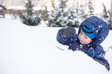 Winter Portrait Of Kid Boy In Colorful Clothes, Outdoors During Snowfall. Active Leisure With Children In On Cold Snowy Days. Happy Child Having Fun Snow