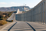 Fototapeta Morze - The international border wall between San Diego, California and Tijuana, Mexico, as it begins its journey from the Pacific coast and travels over nearby hills.  