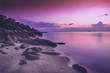 beautiful bright purple pink sunset by the sea, stones on the sand. Stunning scenery