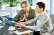 © Seventyfour - Portrait of two businesswomen discussing work and using laptop during business meeting in modern office