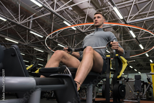 Zdjęcie XXL Niskiego kąta portret przystojny sportowiec ćwiczy używać maszyny pracujące w nowożytnym gym out