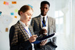 © pressmaster - Youing female agent reading paper with important information with colleague near by