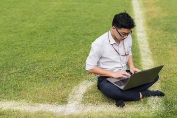 business man is sitting work with computer laptop on soccer field. working concept. copy space for conceptual message.