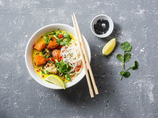 Vegan khao soi soup on a grey background, top view. Vegetarian soup with turmeric, rice noodles, baked pumpkin and cauliflower. Healthy food concept