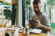 © JKstock - Talented copywriter searching additional information online to create a concept for the new project. Successful blogger reading comments to his new blog post on a tablet connected to wifi.