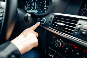 Close up of finger pressing the start stop engine button on car