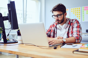 Concentrated young man working on laptop at home office