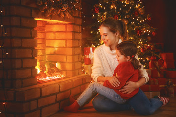 Wall Mural - family mother and child daughter watching fireplace at christmas