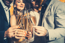 Men And Women Celebrating Birthday Or New Years Party While Clinking Glasses With Sparkling Wine