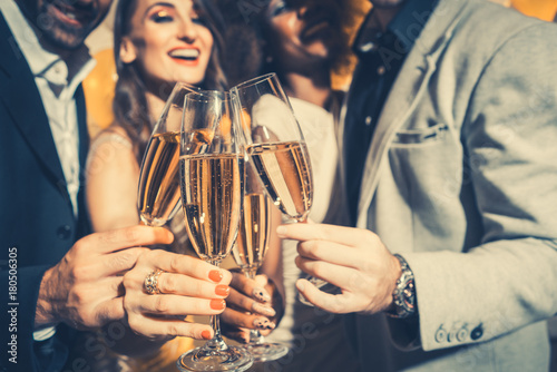 Photo Men and women celebrating birthday or new years party while clinking glasses wit