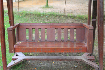 Long wooden chair in the green grass garden.