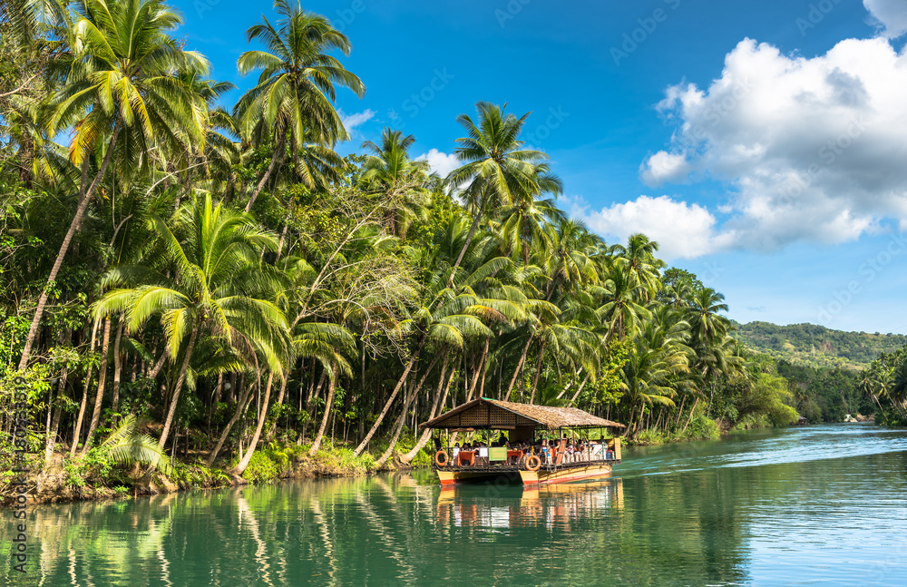 Philippine Raft traditional raft boat with tourists on a jungle green river Loboc at ...