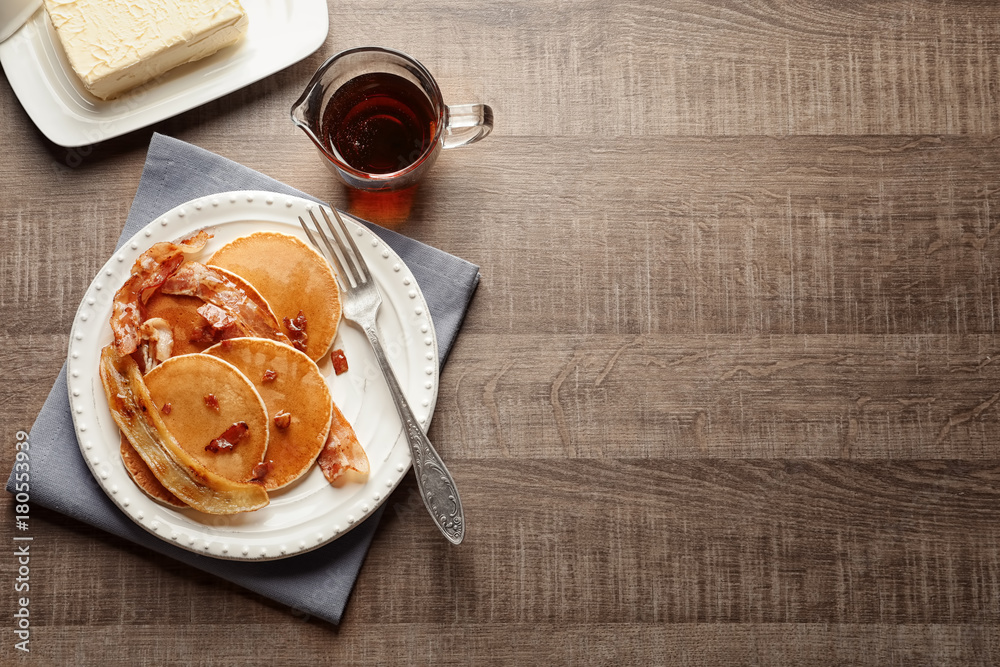 Plate with pancakes, bacon and fried banana on table