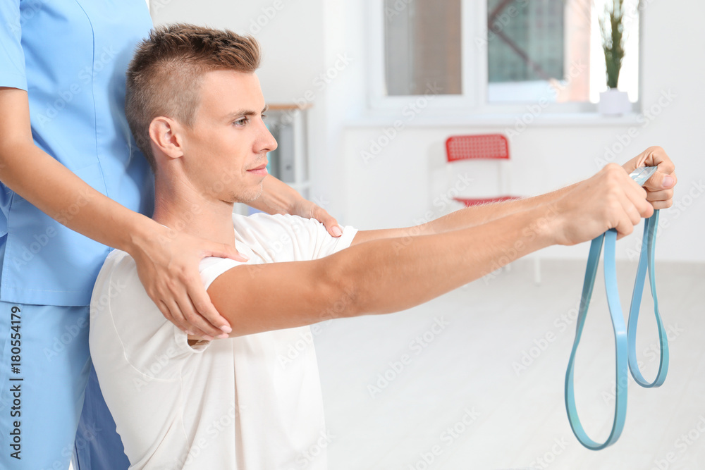 Physiotherapist working with young male patient in clinic