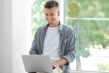 Canvas Print - Young man using laptop near window at home