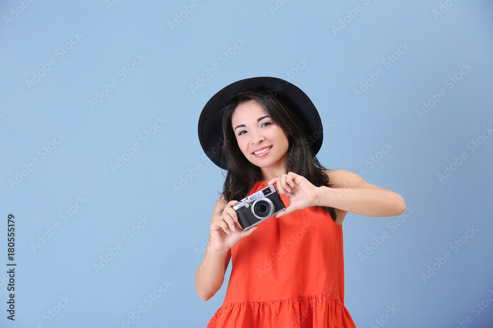 Beautiful female photographer with camera on color background