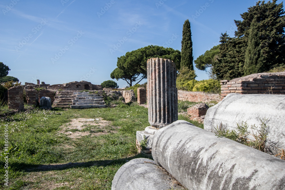 Green field with trees with ancient Roman columns arranged in rows. Old ...