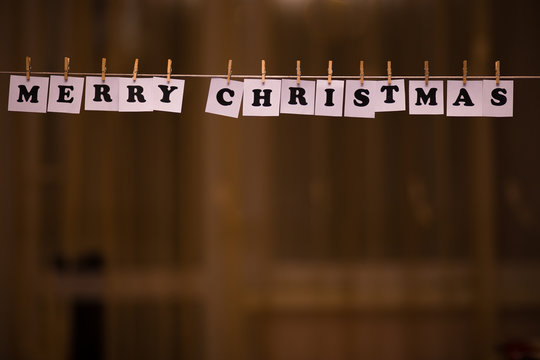 Merry Christmas text on papers with clothespins with garland bokeh on background