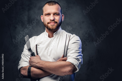 Cuadros en Lienzo Chef cook holds a knife over dark grey background.