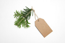 Close-up Of Craft Paper Gift Tag With Rope And Green Fir Branch Isolated On White Background. Christmas Composition, Top View.