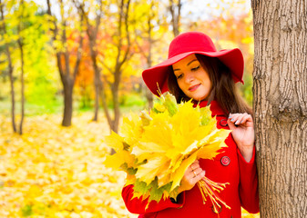 Autumn portrait of beautiful woman over yellow leaves while walking in the park in fall. Positive emotions and happiness concept.