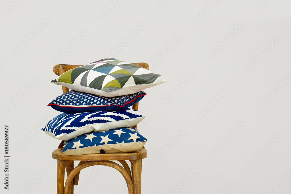 Wooden chair with colorful pillows on light background