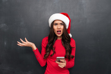 Canvas Print - Displeased brunette woman in red blouse and christmas hat