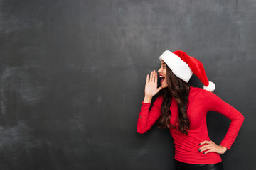 Canvas Print - Happy brunette woman in red blouse and christmas hat