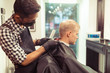 © uv_group - Handsome hairdresser cutting hair of male client. Men hairstylist serving client at vintage barber shop.