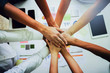 © Jirapong - top view of business people putting their hands together. Friends with stack of hands showing unity and teamwork via tablet, smartphone and spacesheet  in office.