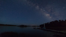 Milky Way Above Kolob Reservoir In Southern Utah With A Couple Of Sailboats Tied Up At A Dock.