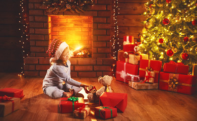 Wall Mural - happy child girl open christmas gifts at night at christmas tree