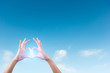 © PRASERT - two hands making a heart shape in the blue sky