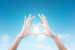 © PRASERT - two hands making a heart shape in the blue sky