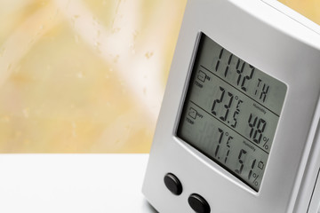 weather station device with weather conditions inside and outside. background of a window with raind